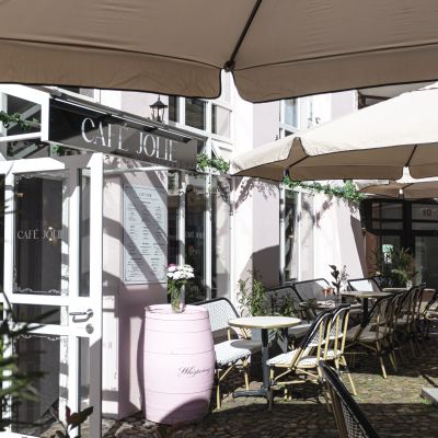 Mit Blumen und Pflanzen dekorierter Eingang zum Café Jolie